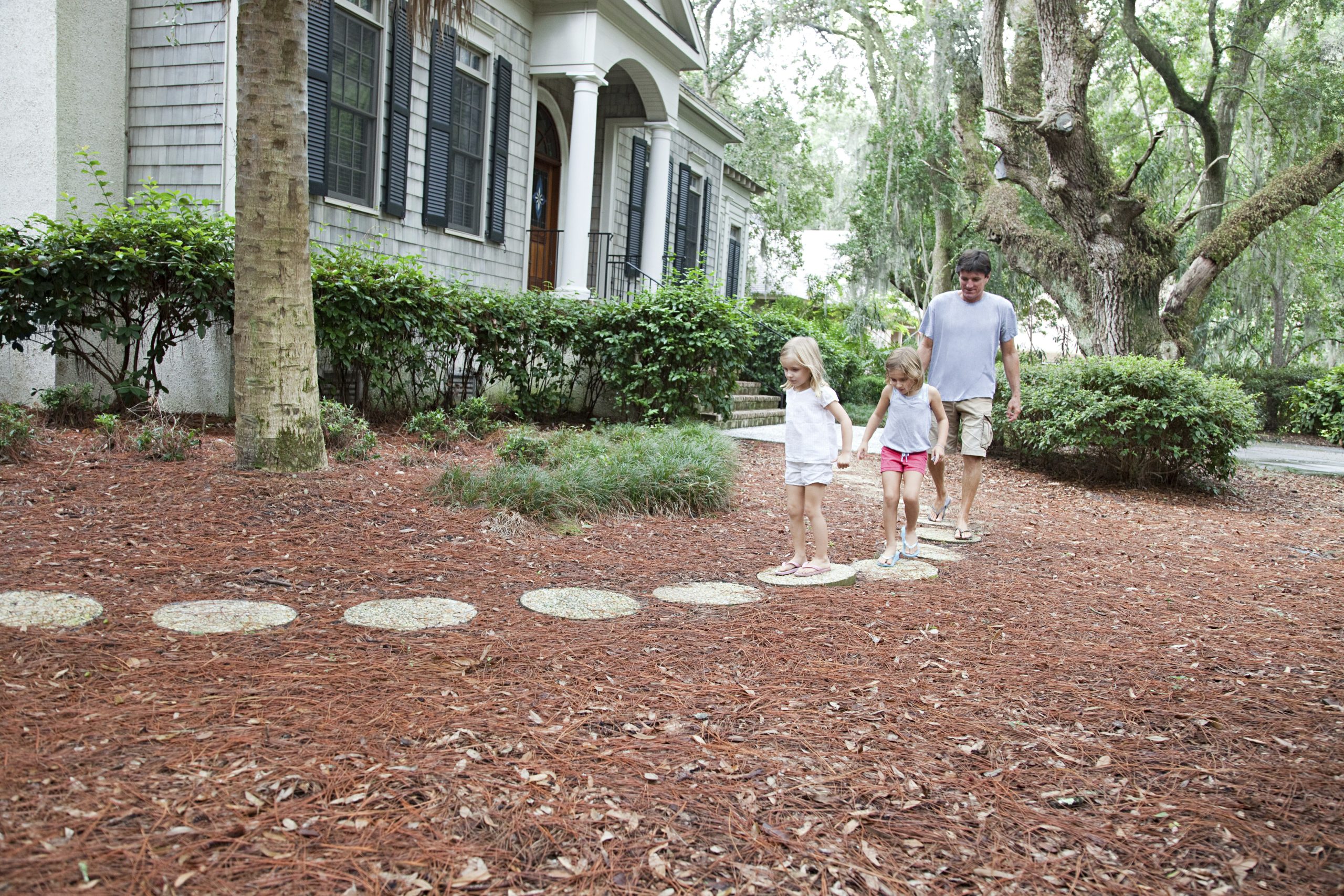 Father and daughters walking on garden path
